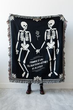 two skeletons holding hands on a black and white blanket