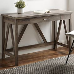 a wooden desk with two drawers and a book on it in a white walled room