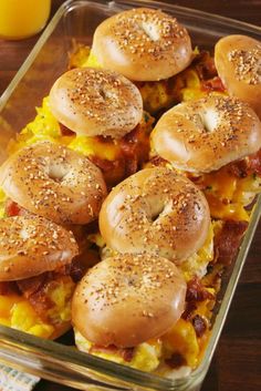 several bagels with cheese and bacon in a casserole dish next to an orange juice