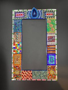 a multicolored photo frame with a mirror in the middle