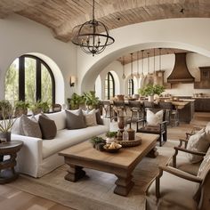 a living room filled with furniture and lots of windows next to a kitchen area covered in potted plants