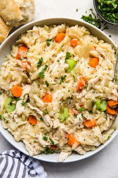 a bowl filled with pasta and vegetables next to some bread on the side, along with a fork