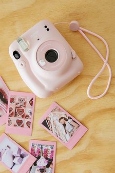 a polaroid camera sitting on top of a wooden table next to pictures and cords