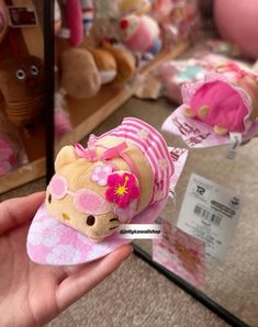 a hand holding a hello kitty doll in front of some other stuffed animals and toys