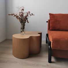 a vase with flowers sitting on top of a table next to an orange couch and chair