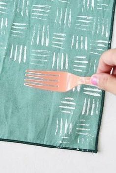 a person holding a fork on top of a piece of green paper with white lines