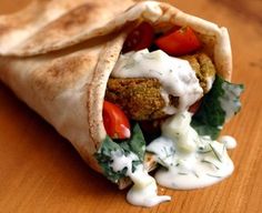 a pita filled with meat and vegetables on top of a wooden table