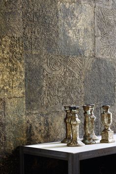 three vases on a table in front of a stone wall