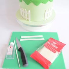 a cake sitting on top of a green cutting board next to a knife and other items