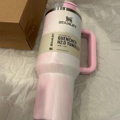 a pink and white coffee cup sitting next to a cardboard box on a sheet covered floor