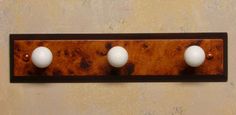 three golf balls are mounted to a wooden plaque with holes in the wood and one is white