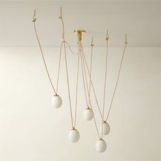 four lights hanging from the ceiling in a room with white walls and gold fixtures on it