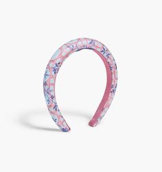 a pink and blue headband with flowers on it, against a white background the band is made out of plastic