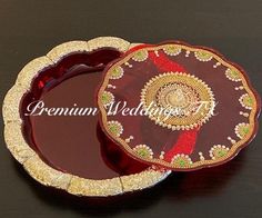 two red and gold plates sitting on top of a black table next to each other