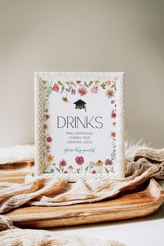 a drink sign sitting on top of a wooden tray next to a pile of blankets