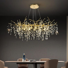 an elegant chandelier hangs over a dining room table with chairs and a vase