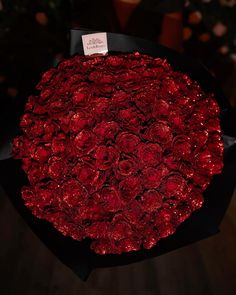 a large bouquet of red roses in a black paper wrapper with a price tag on it