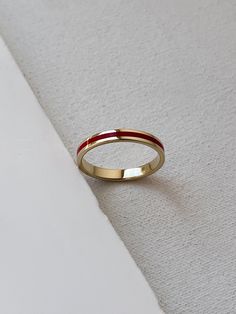 a gold and red wedding ring sitting on top of a white cloth covered tablecloth