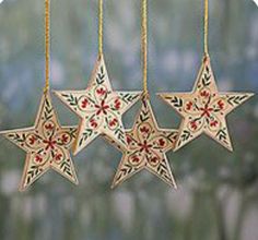 three wooden stars hanging from strings on a string with red and green flowers painted on them