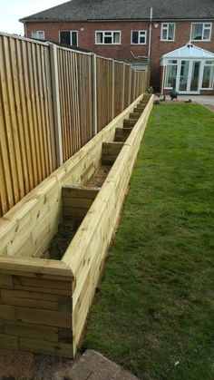 a wooden bench sitting in the middle of a grass covered yard next to a fence