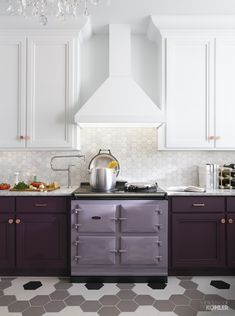 a stove top oven sitting inside of a kitchen next to white cupboards and counter tops