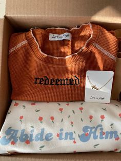 an orange sweater is in a box with some other items on it and the name renemen written across the chest