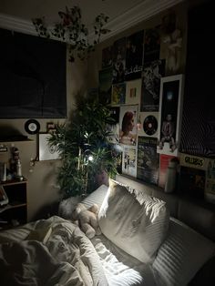 an unmade bed with white sheets and pillows in a room filled with posters on the wall