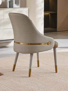 a beige chair with gold trim around the legs on a rug in a living room