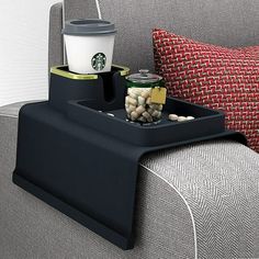 there is a coffee cup and some snacks on the tray in the chair next to the couch