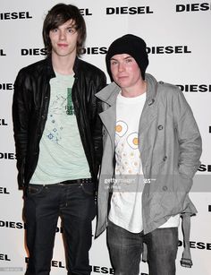 two young men standing next to each other in front of a diesel wallpaper sign