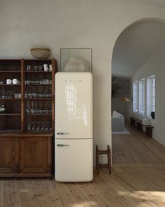 a white refrigerator freezer sitting in a kitchen next to a wooden cabinet and shelves