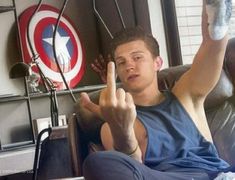 a young man sitting on a couch making the peace sign with his hand in front of him