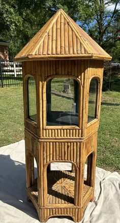 a small wooden tower sitting on top of a blanket in the grass next to a tree