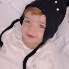 a young boy wearing a black hat laying on top of a bed