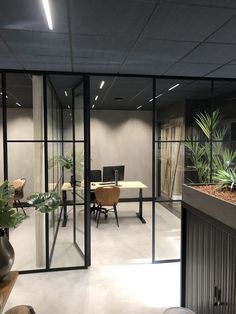 an office with glass walls and potted plants