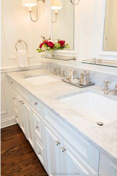 a white bathroom with two sinks and mirrors