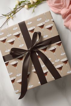 a gift box wrapped in brown ribbon and decorated with martini glasses