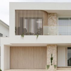 a white house with wooden shutters and two cars parked in front of the garage