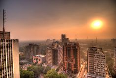 the sun is setting over an urban area with high rise buildings and tall skyscrapers