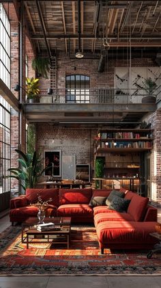 an industrial living room with red couches and rugs in front of large windows