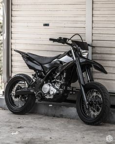 a black motorcycle parked in front of a garage