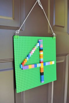 a green sign made out of legos hanging on a door frame with a string attached to it