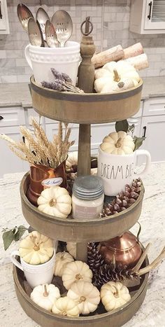 a three tiered tray filled with coffee cups and other fall decorations on top of a kitchen counter