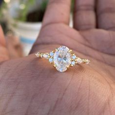 a person's hand holding an engagement ring with three stones on the top and bottom