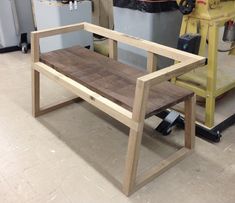 a wooden bench sitting next to a machine in a room filled with other tools and equipment