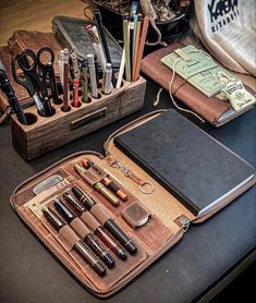 an assortment of pens, pencils, and scissors in a leather case