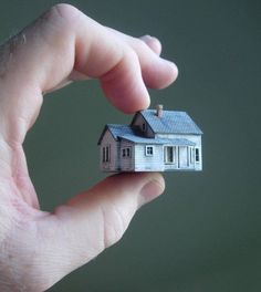 a small house is held in the palm of someone's hand with a tiny roof