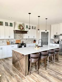 a large kitchen with white cabinets and wooden flooring on the island in front of an oven