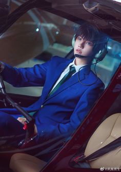 a man in a blue suit and headphones sitting in a car