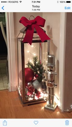 a lantern with a red bow on top and christmas decorations in the bottom, along with other items